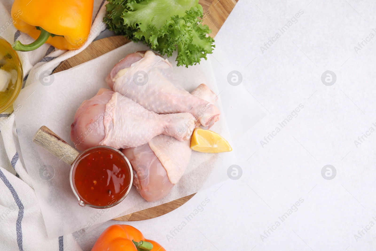 Photo of Flat lay composition with marinade and raw chicken drumsticks on white table. Space for text