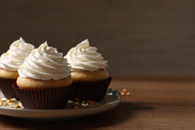 Photo of Delicious cupcakes decorated with cream on wooden table