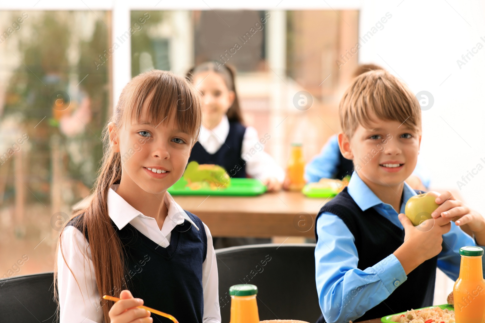 Photo of Happy children at table with healthy food in school canteen