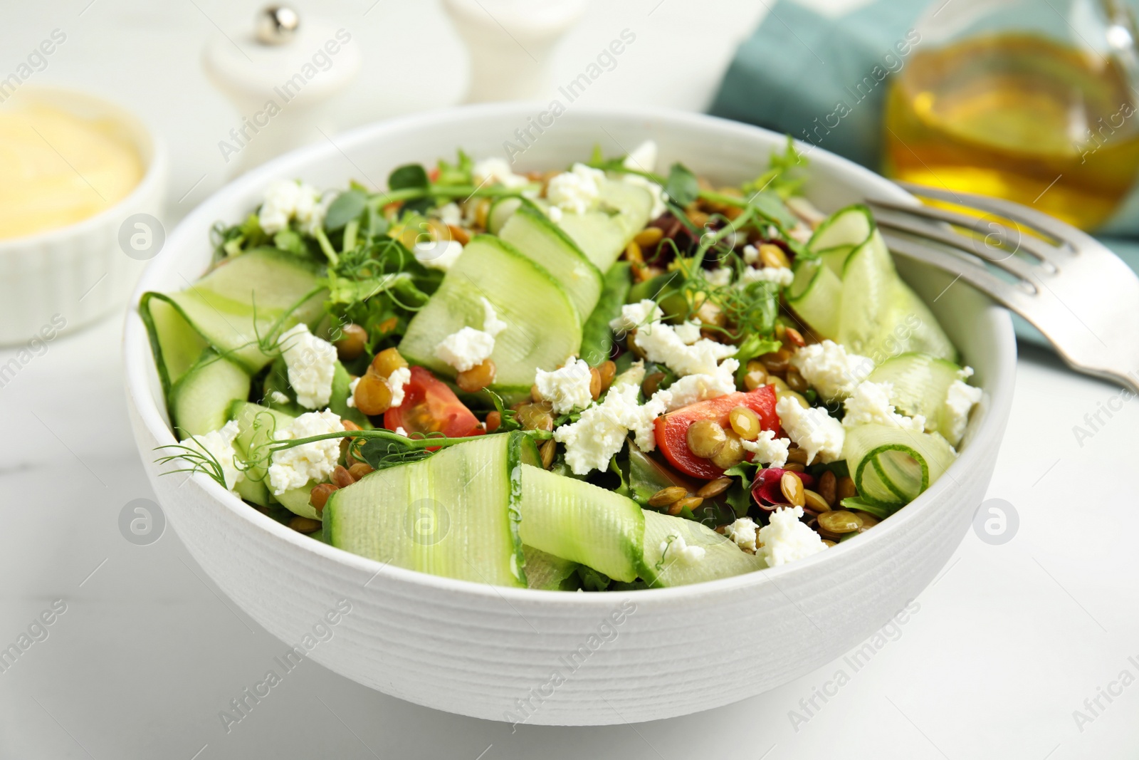 Photo of Delicious salad with lentils, vegetables and feta cheese served on white table, closeup