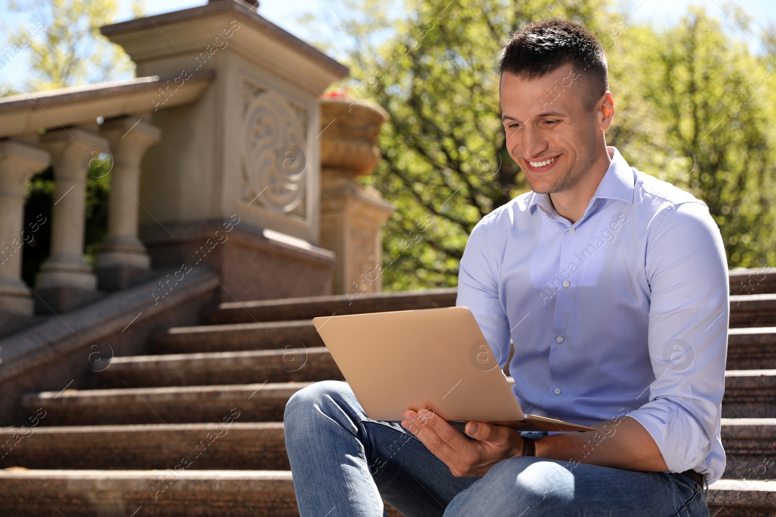 Photo of Man working with laptop on steps outdoors