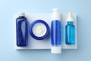 Set of cosmetic products on light blue background, top view