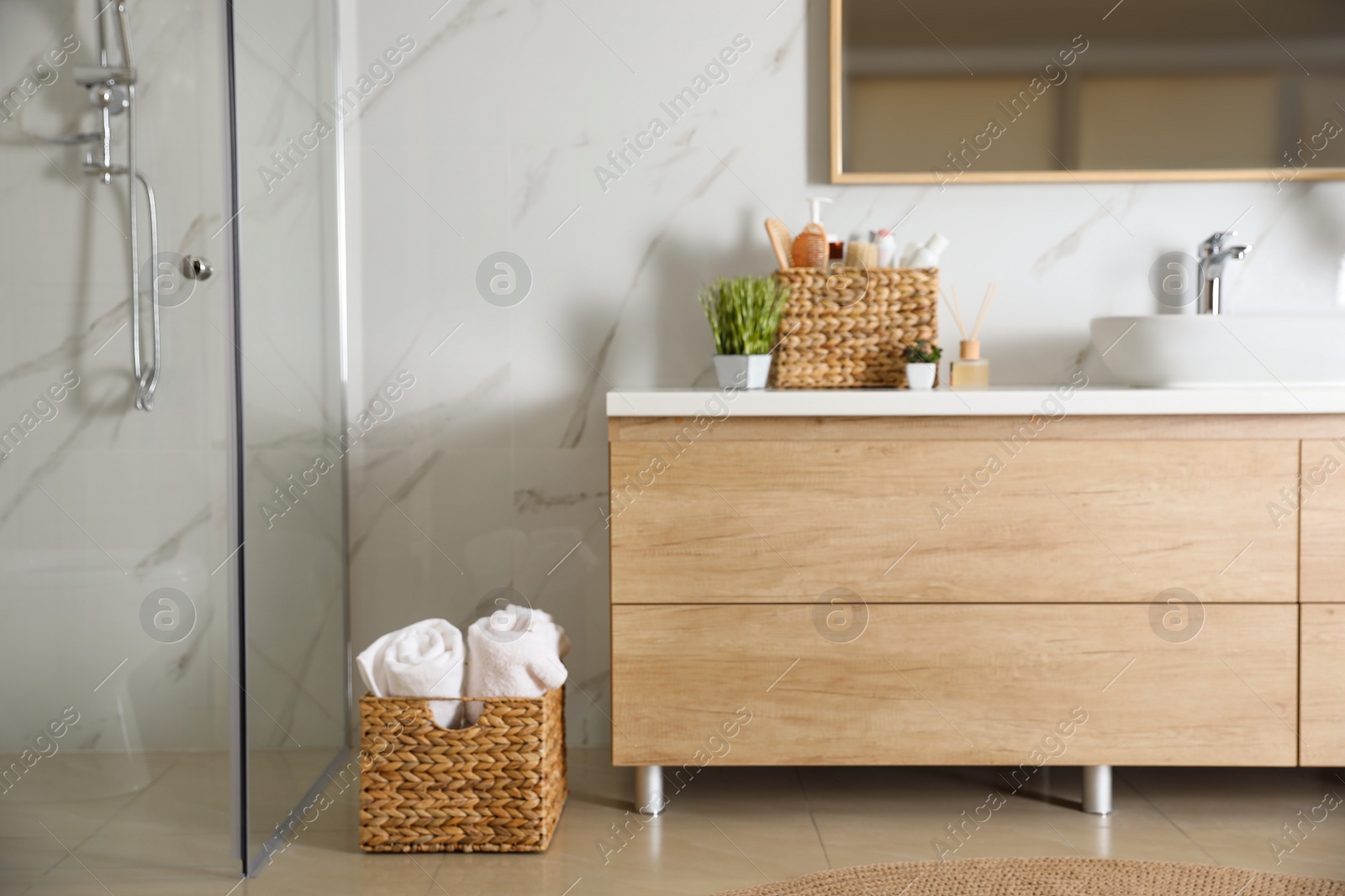 Photo of Elegant modern bathroom with wooden cabinet near marble wall