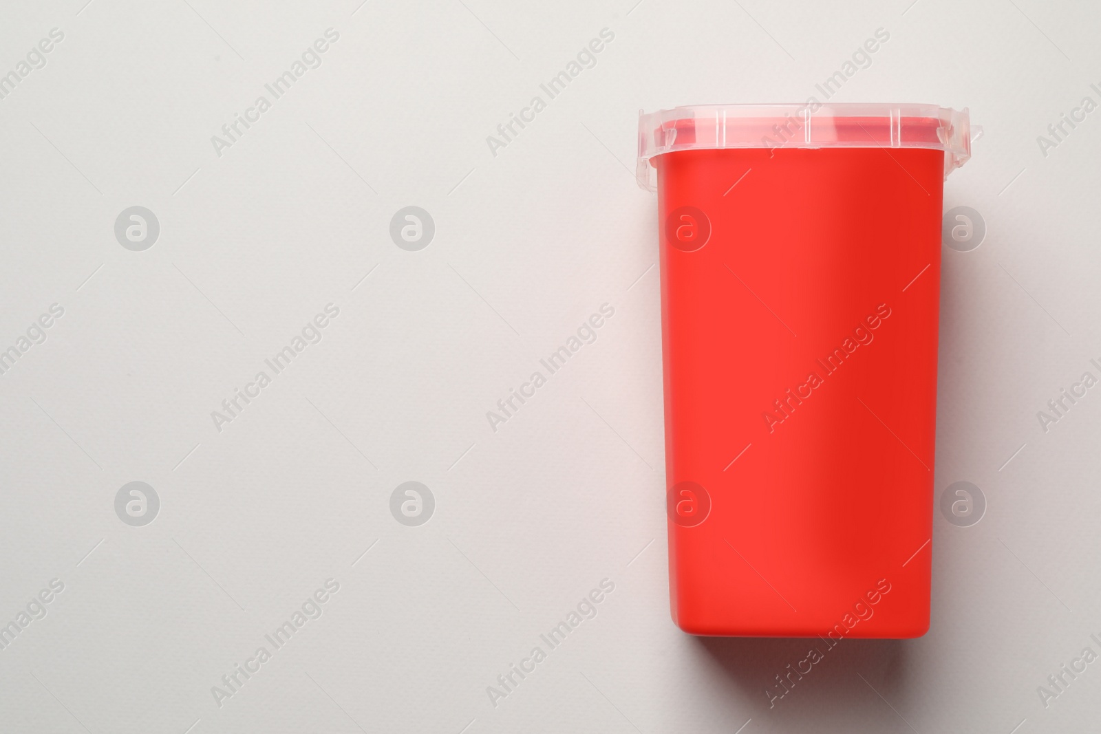 Photo of Sharps container for used syringe on light background, top view. Space for text