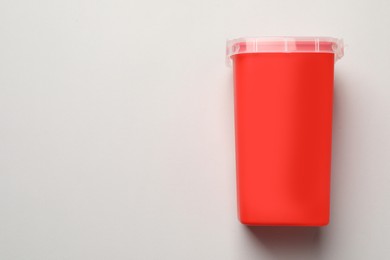 Sharps container for used syringe on light background, top view. Space for text