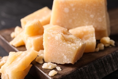 Pieces of delicious parmesan cheese on wooden board, closeup