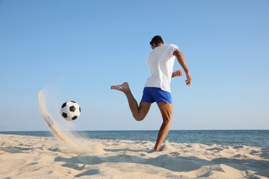 Man playing football on beach near sea