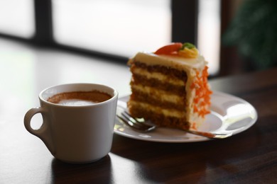 Cup of hot coffee and delicious cake on wooden table, closeup