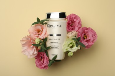 MYKOLAIV, UKRAINE - SEPTEMBER 07, 2021: Kerastase shampoo and beautiful flowers on beige background, flat lay. Hair care cosmetic product