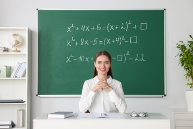 Photo of Young math’s teacher giving lesson at table in classroom