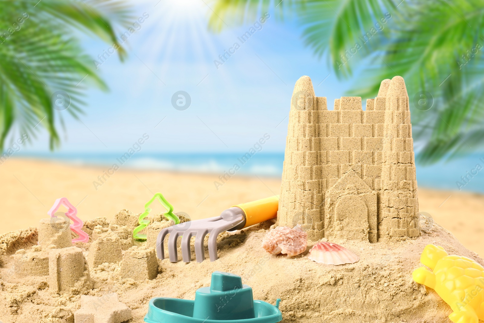 Image of Sand castle with toys on ocean beach. Outdoor play