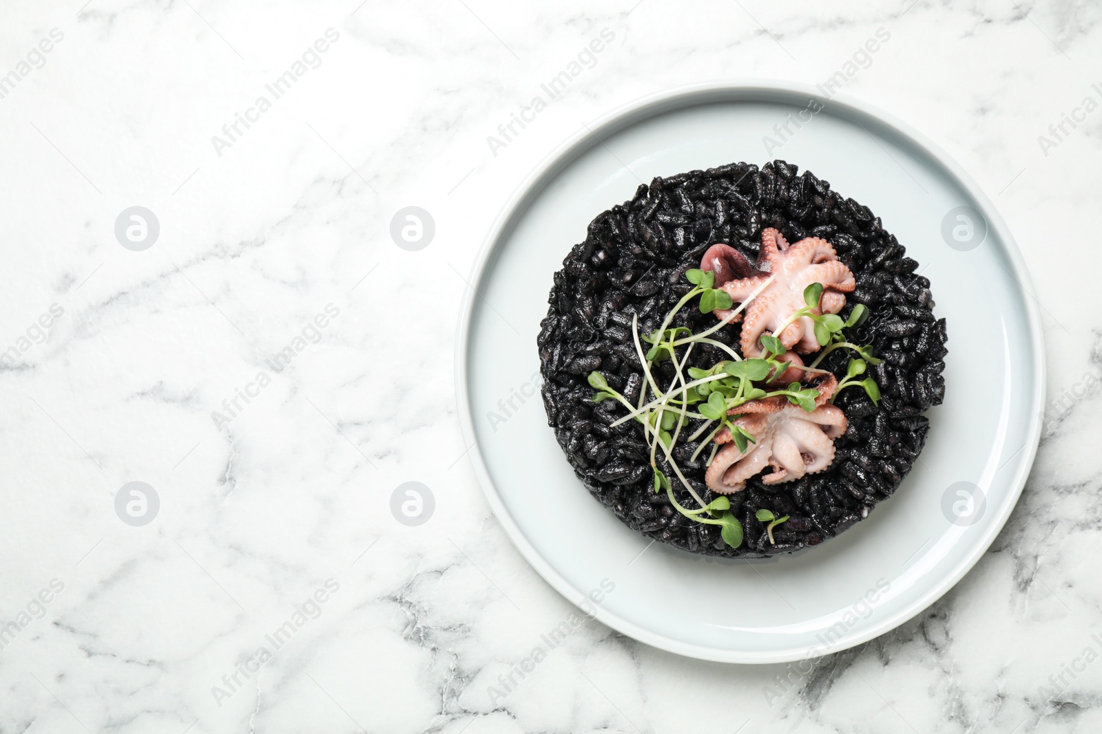 Photo of Delicious black risotto with seafood on white marble table, top view. Space for text