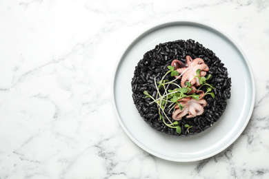 Delicious black risotto with seafood on white marble table, top view. Space for text