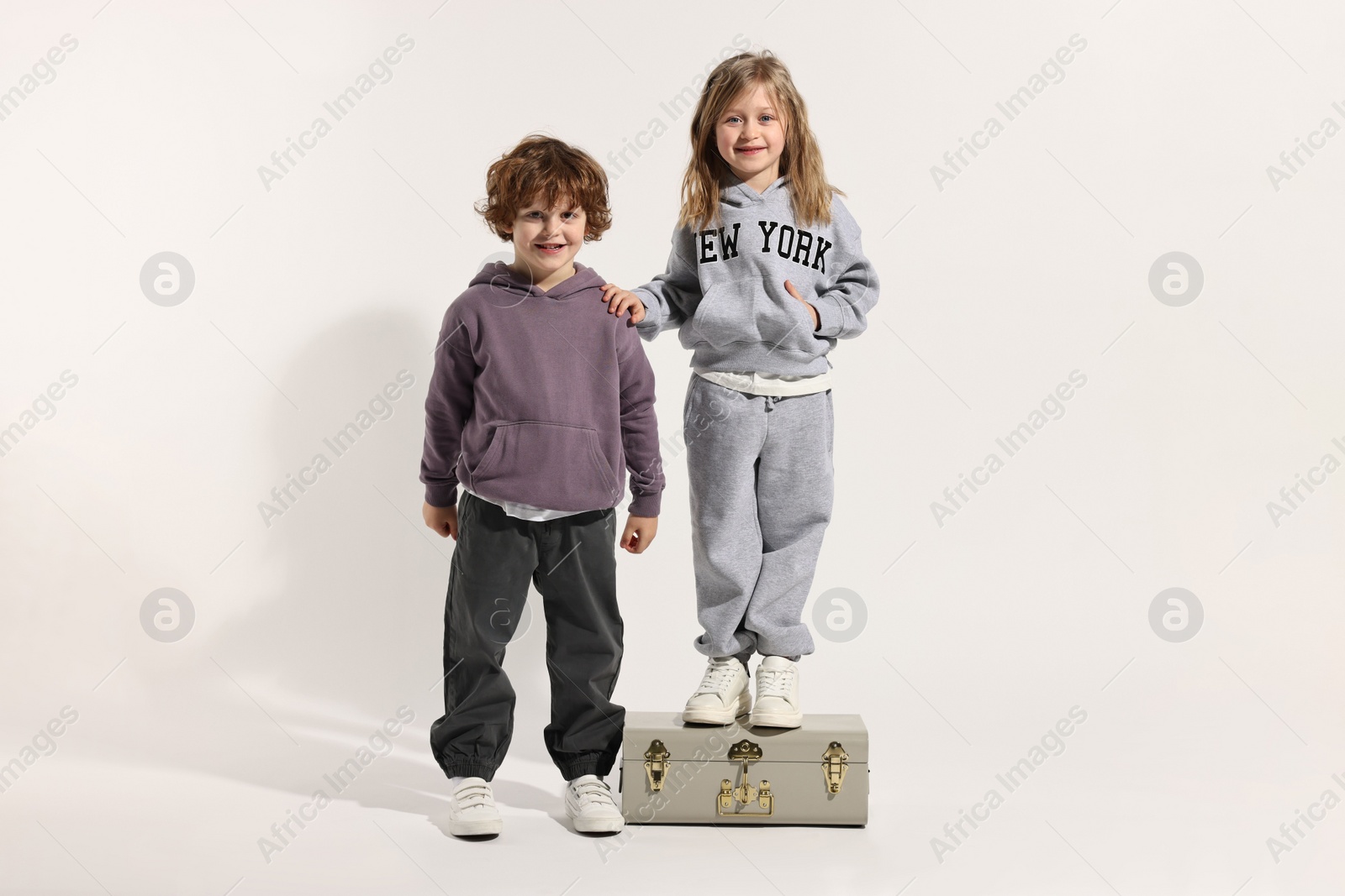 Photo of Fashion concept. Stylish children with vintage suitcase on white background