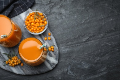 Delicious sea buckthorn juice and fresh berries on black table, top view. Space for text