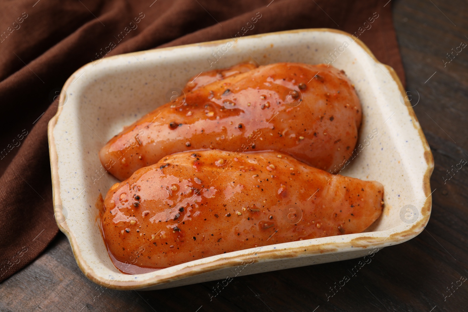 Photo of Raw marinated chicken fillets on wooden table