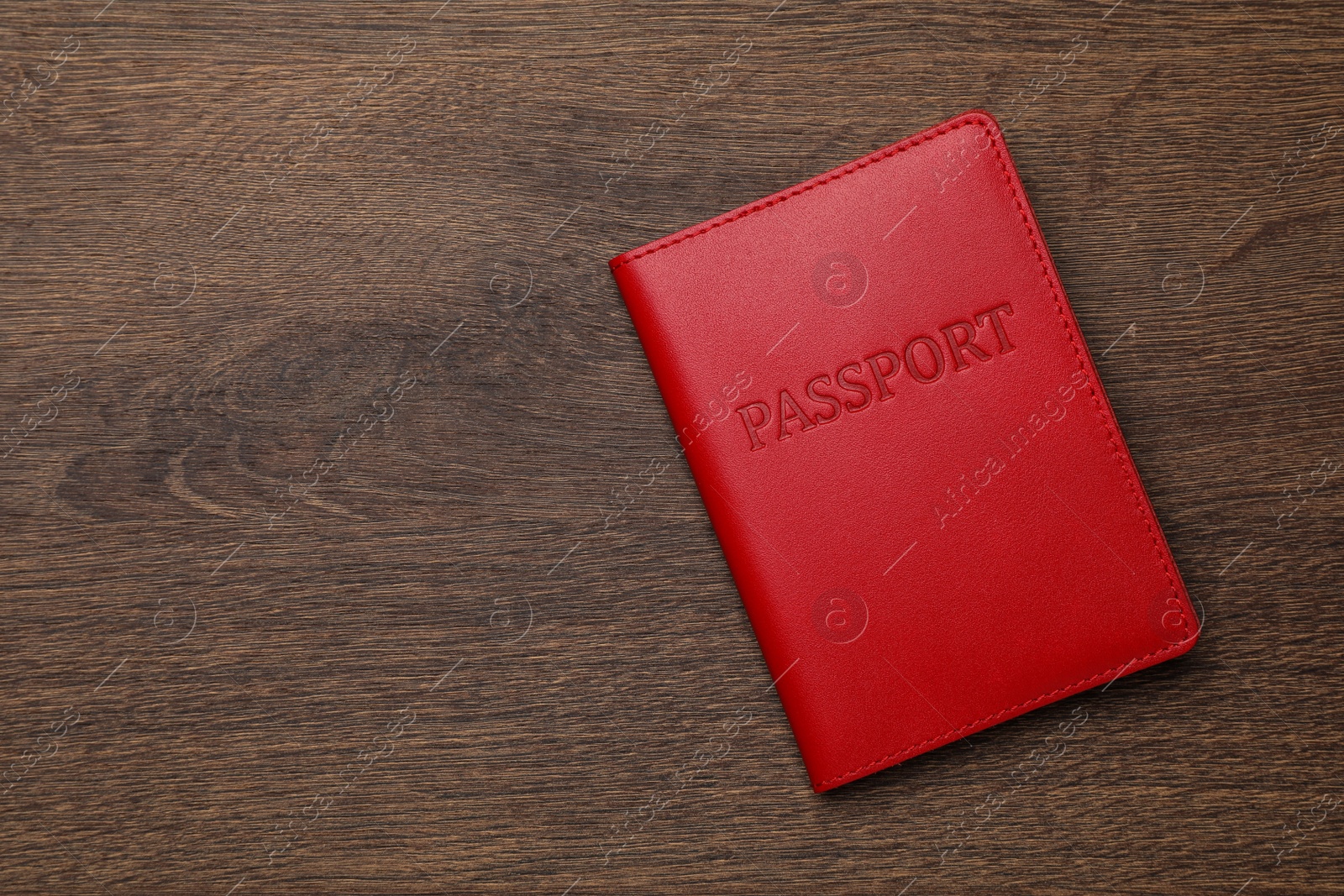 Photo of Passport in red leather case on wooden table, top view. Space for text