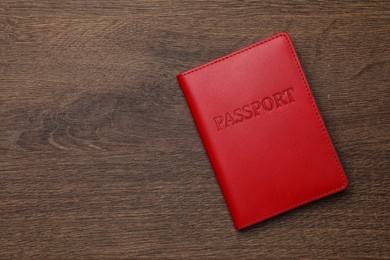 Photo of Passport in red leather case on wooden table, top view. Space for text