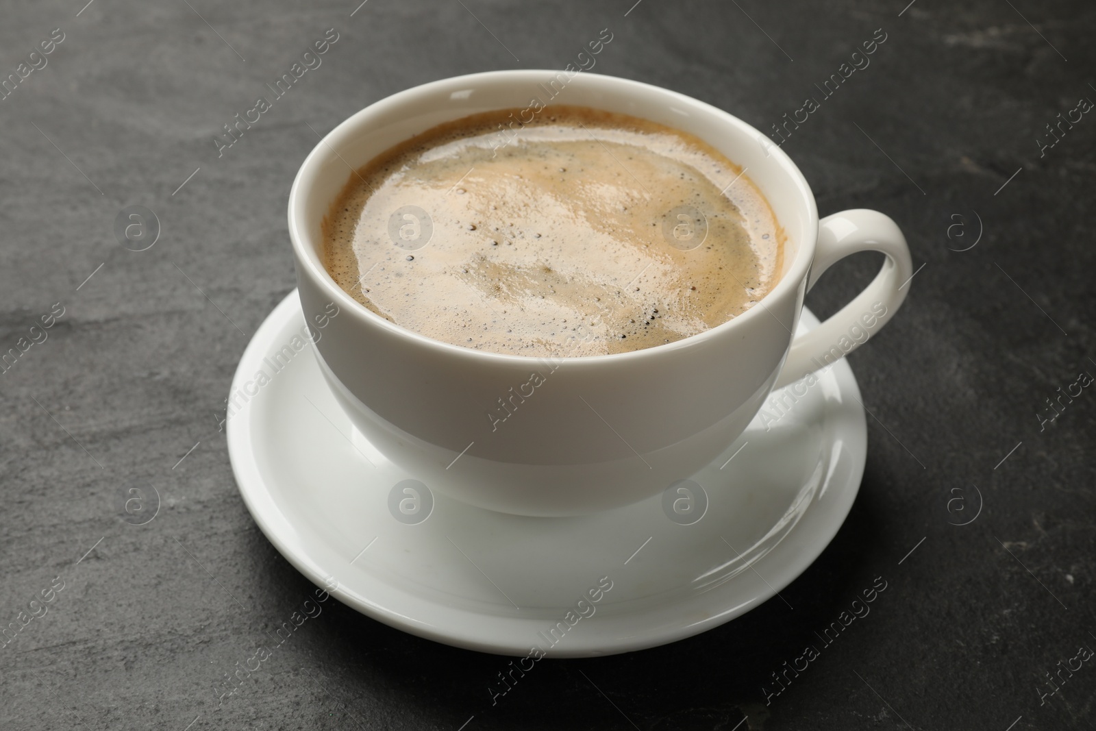 Photo of Cup of aromatic coffee on black table, closeup