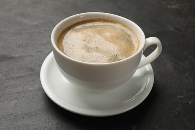 Photo of Cup of aromatic coffee on black table, closeup