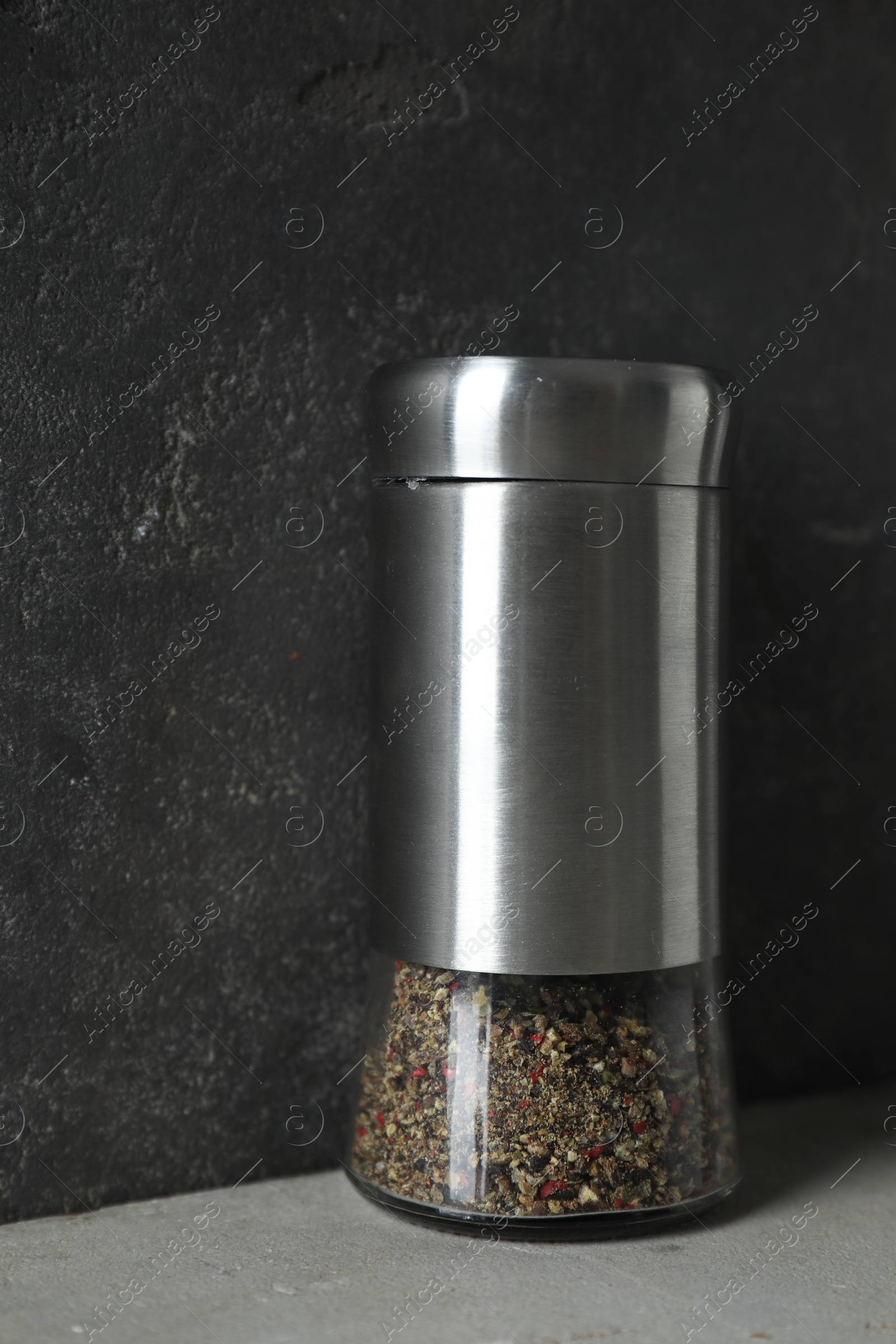 Photo of Pepper shaker on light table against grey background, closeup