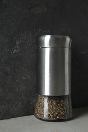 Photo of Pepper shaker on light table against grey background, closeup