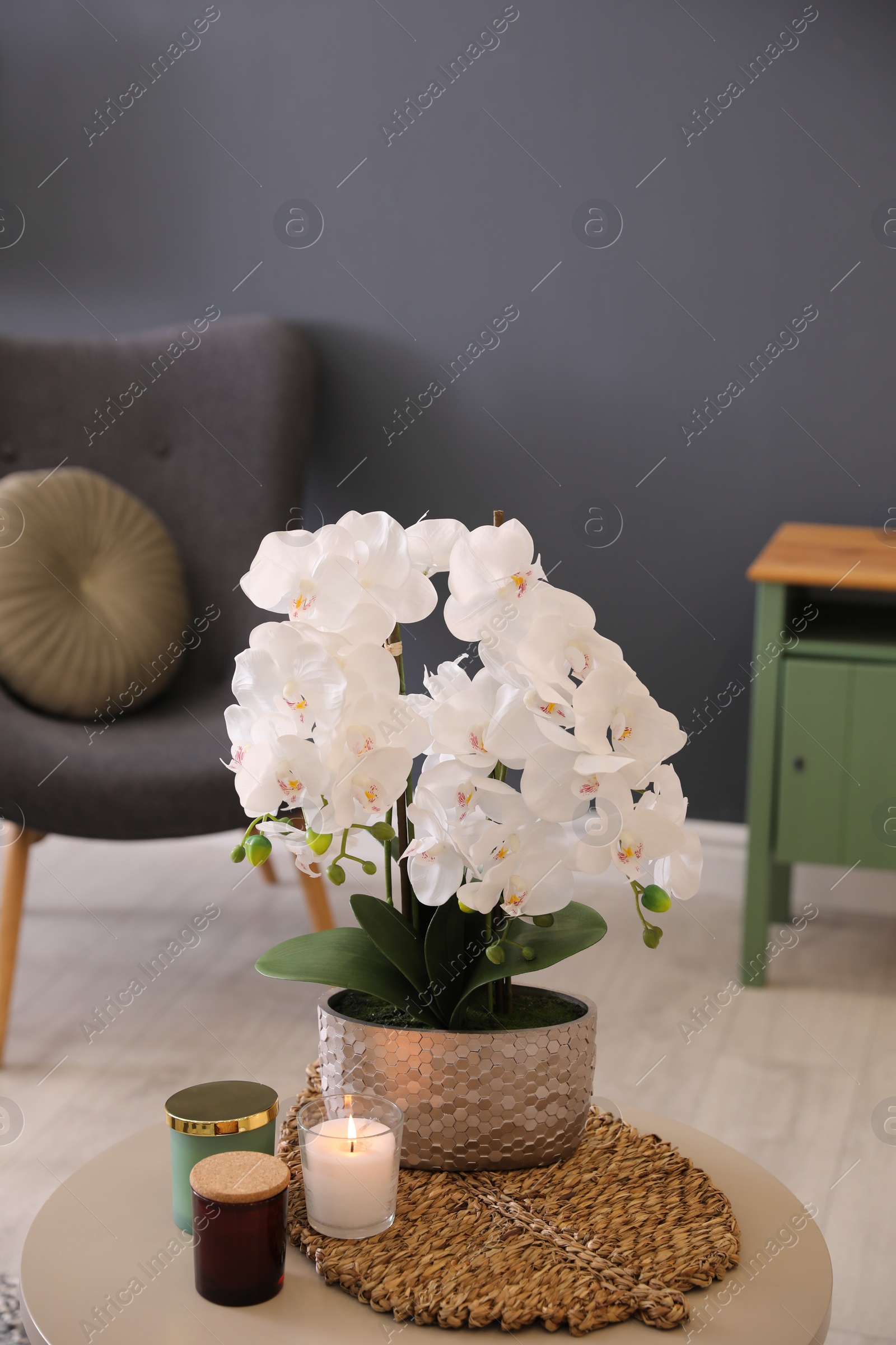 Photo of Beautiful white orchids and candles on table in room. Interior design