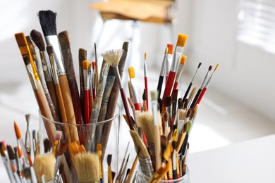 Photo of Different paintbrushes on white table indoors, closeup. Artist's workplace
