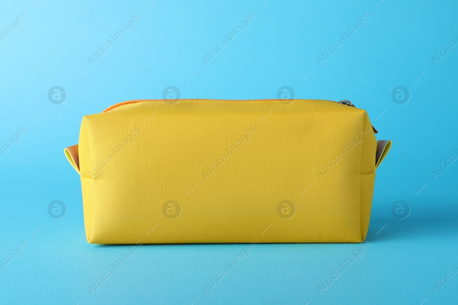 Photo of Yellow cosmetic bag on light blue background