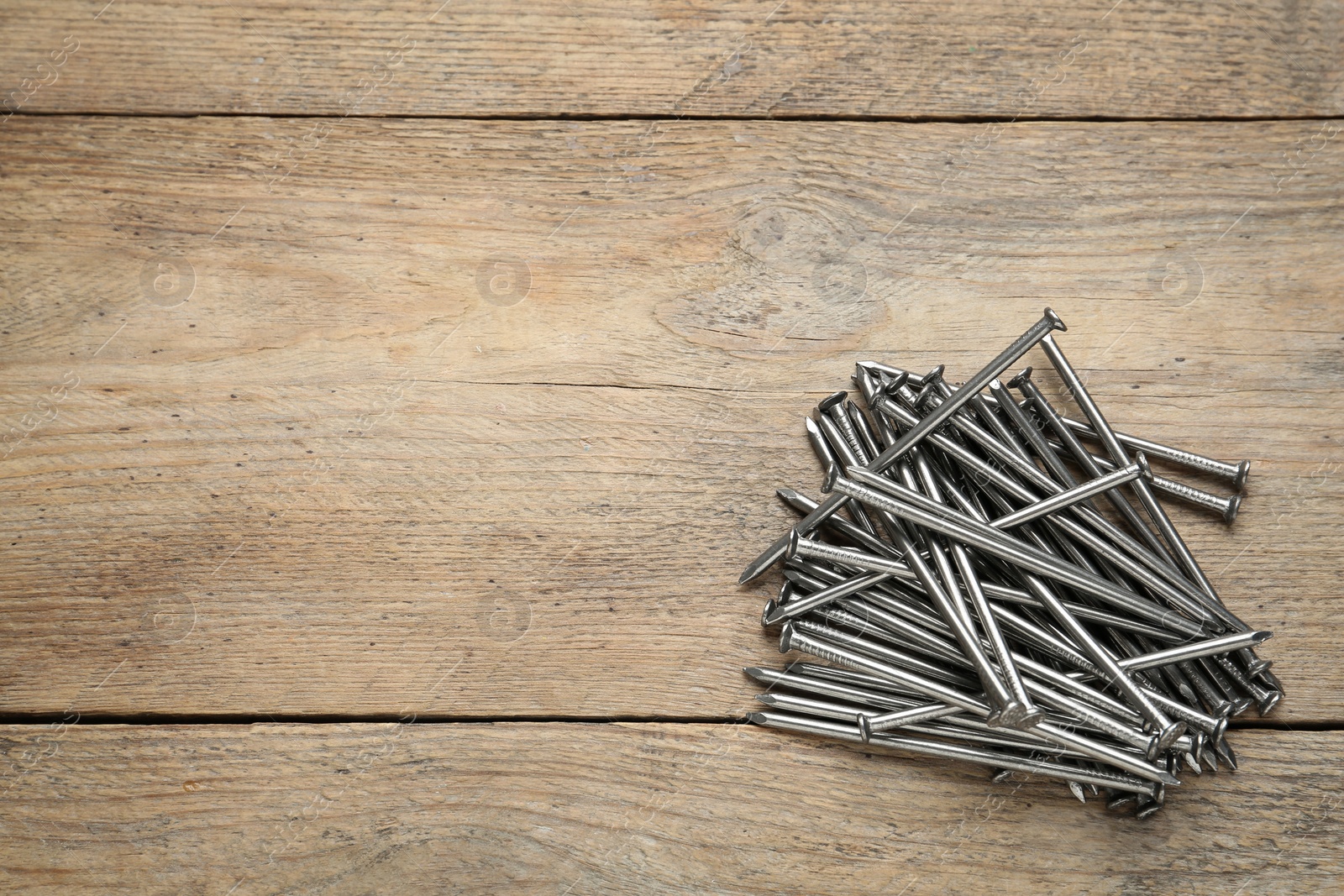 Photo of Many metal nails on wooden background, flat lay. Space for text