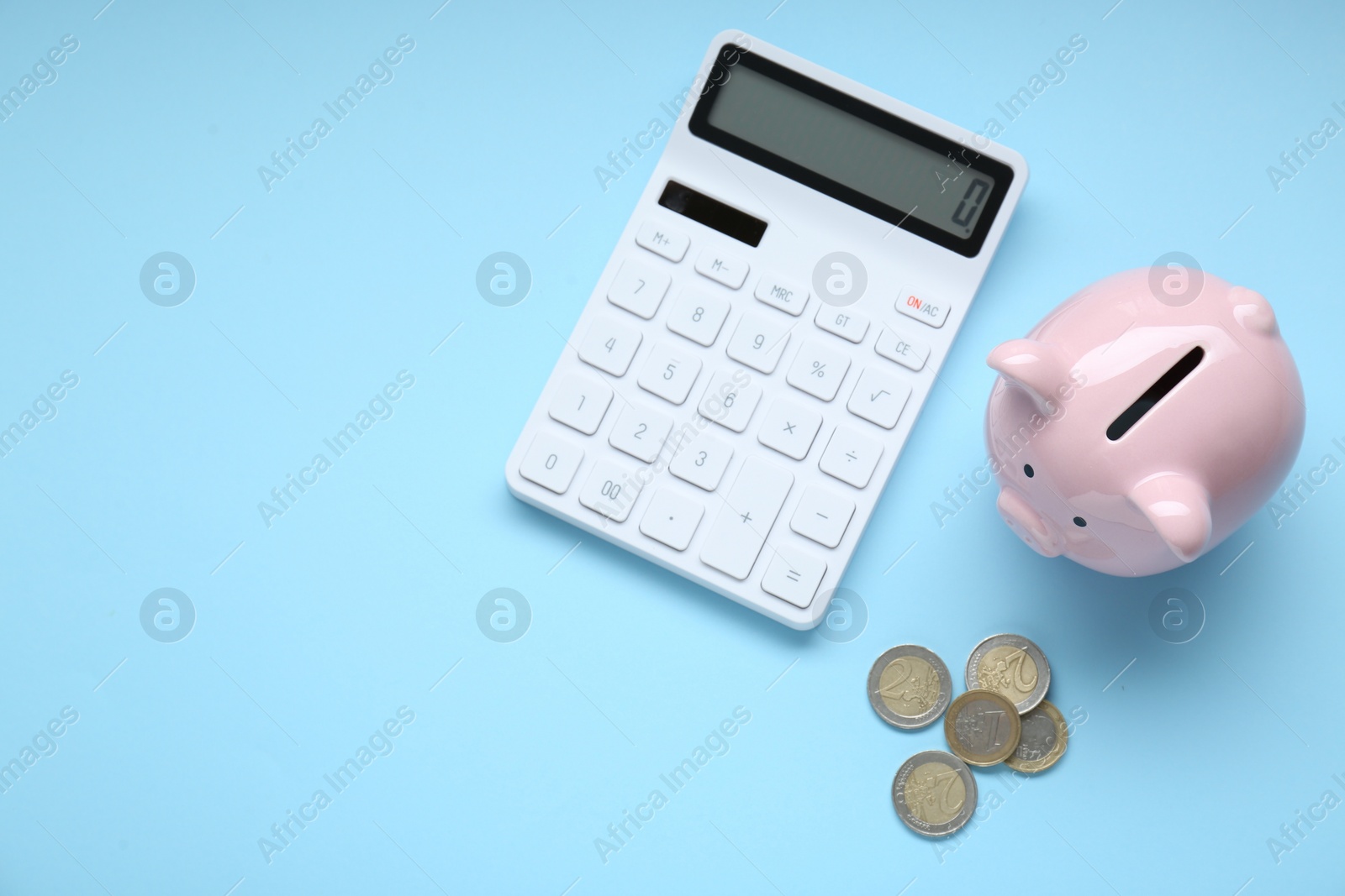 Photo of Piggy bank, coins and calculator on light blue background, flat lay. Space for text