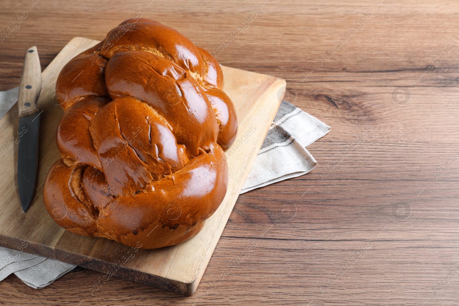 Photo of Homemade braided bread on wooden table, space for text. Traditional Shabbat challah