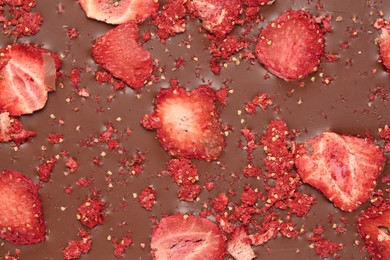 Chocolate bar with freeze dried strawberries as background, closeup