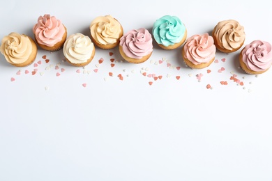 Photo of Flat lay composition with delicious birthday cupcakes and space for text on white background