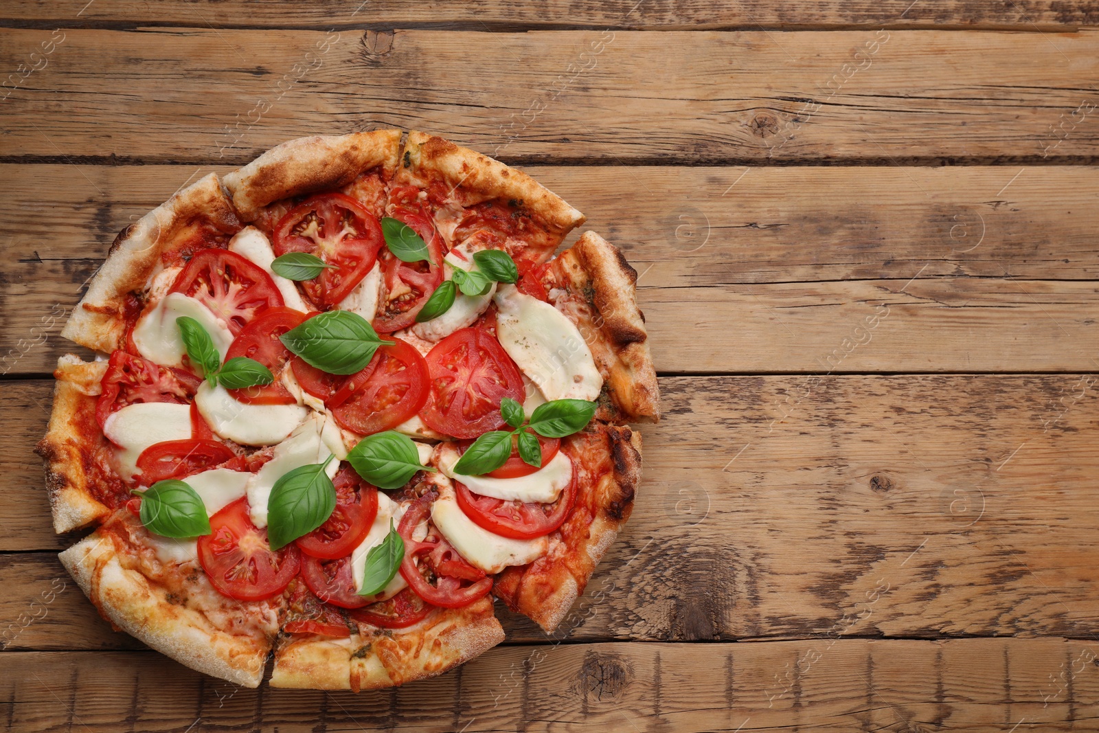 Photo of Delicious Caprese pizza on wooden table, top view. Space for text