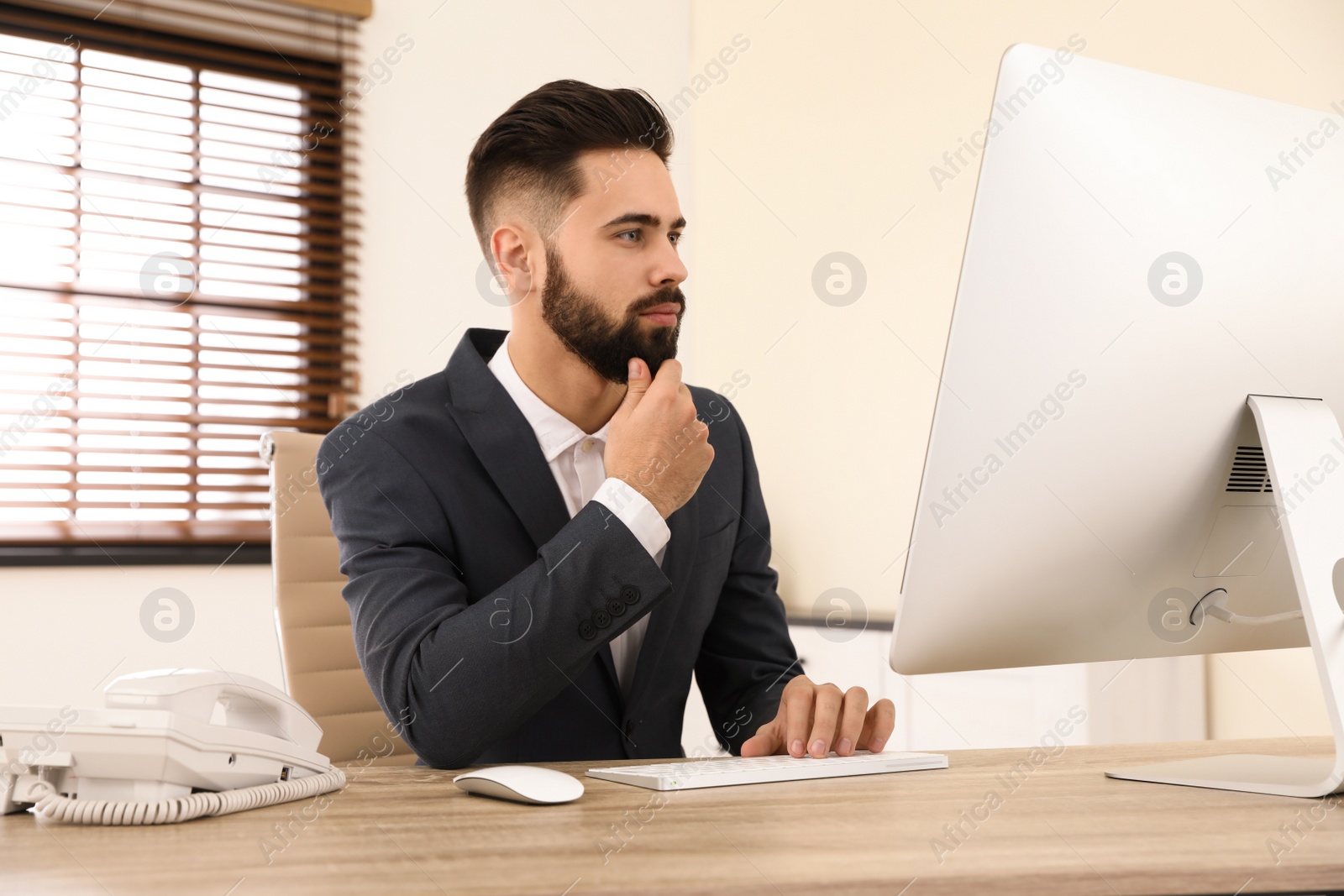 Photo of Handsome businessman working with computer at table in office