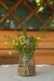 Photo of Bouquet of beautiful wildflowers in glass vase on table indoors