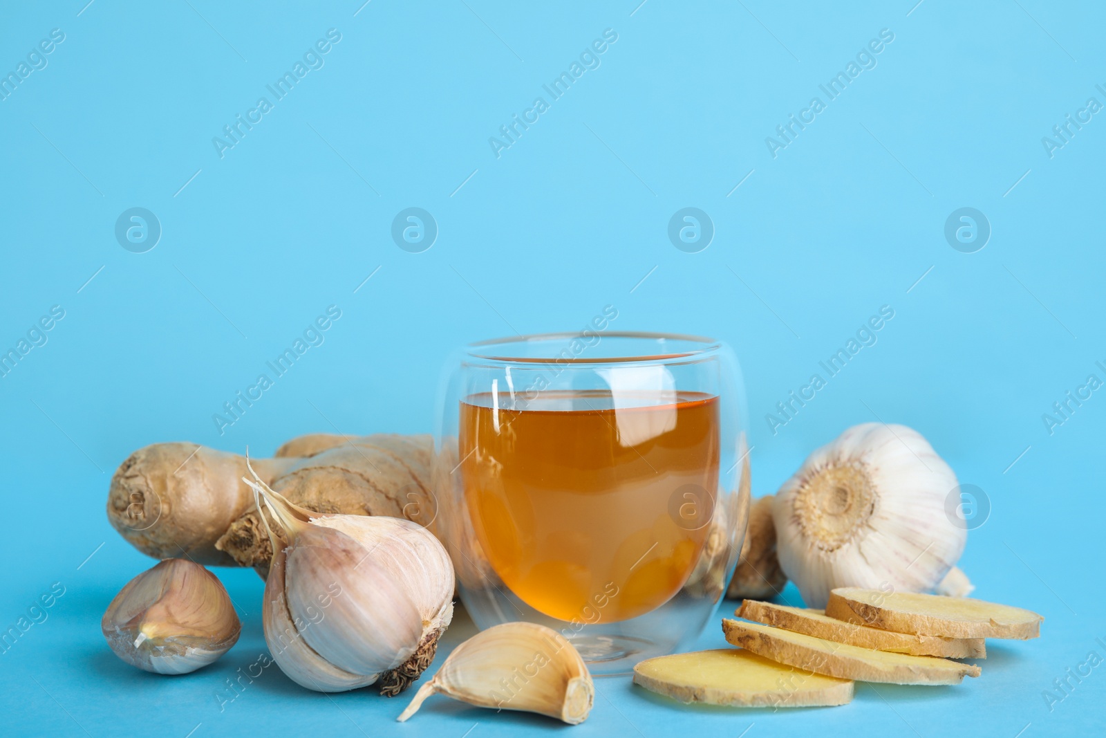 Photo of Fresh garlic and other natural cold remedies on light blue background. Space for text