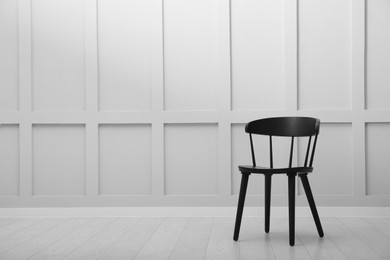 Photo of Black wooden chair near white wall indoors. Space for text