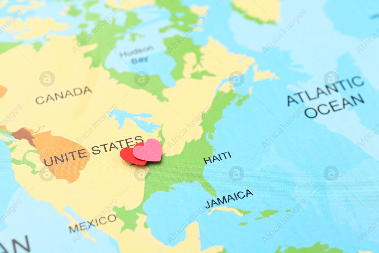 Photo of Honeymoon concept. Two red paper hearts on world map, closeup