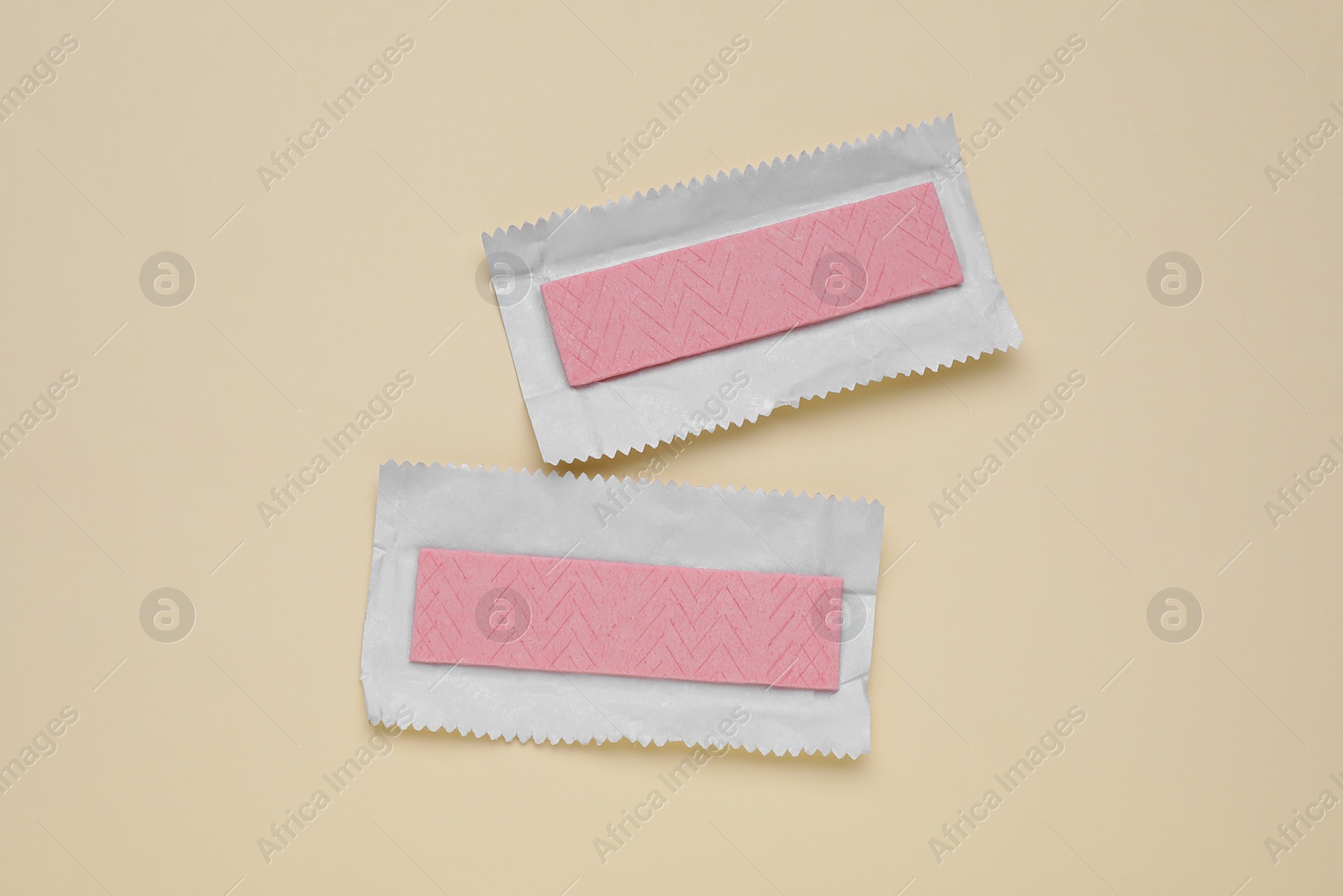 Photo of Unwrapped sticks of tasty chewing gum on beige background, flat lay