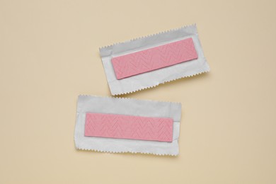 Photo of Unwrapped sticks of tasty chewing gum on beige background, flat lay