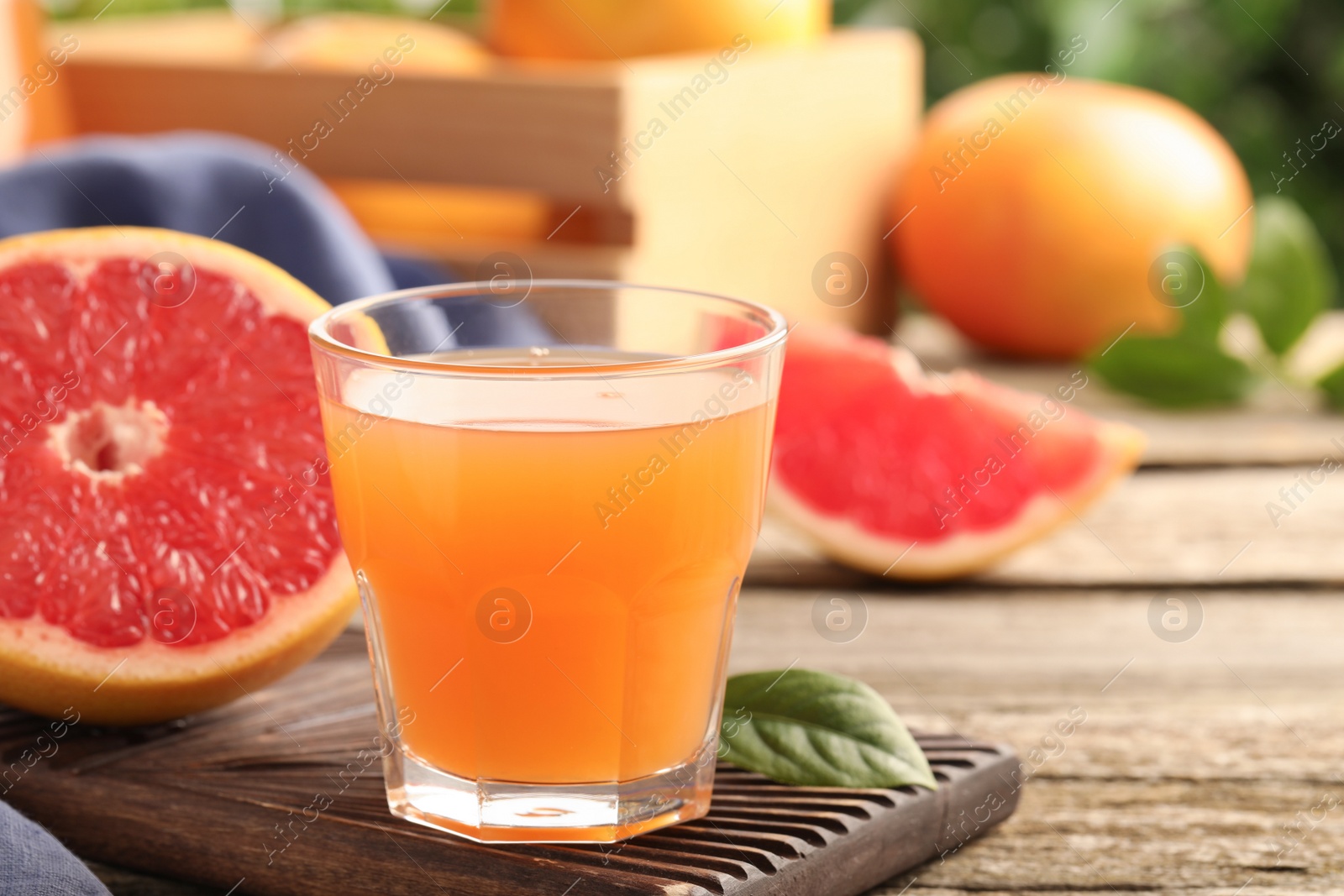 Photo of Glass of delicious grapefruit juice on wooden table, space for text