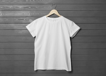 Photo of Hanger with stylish white T-shirt on gray wooden wall