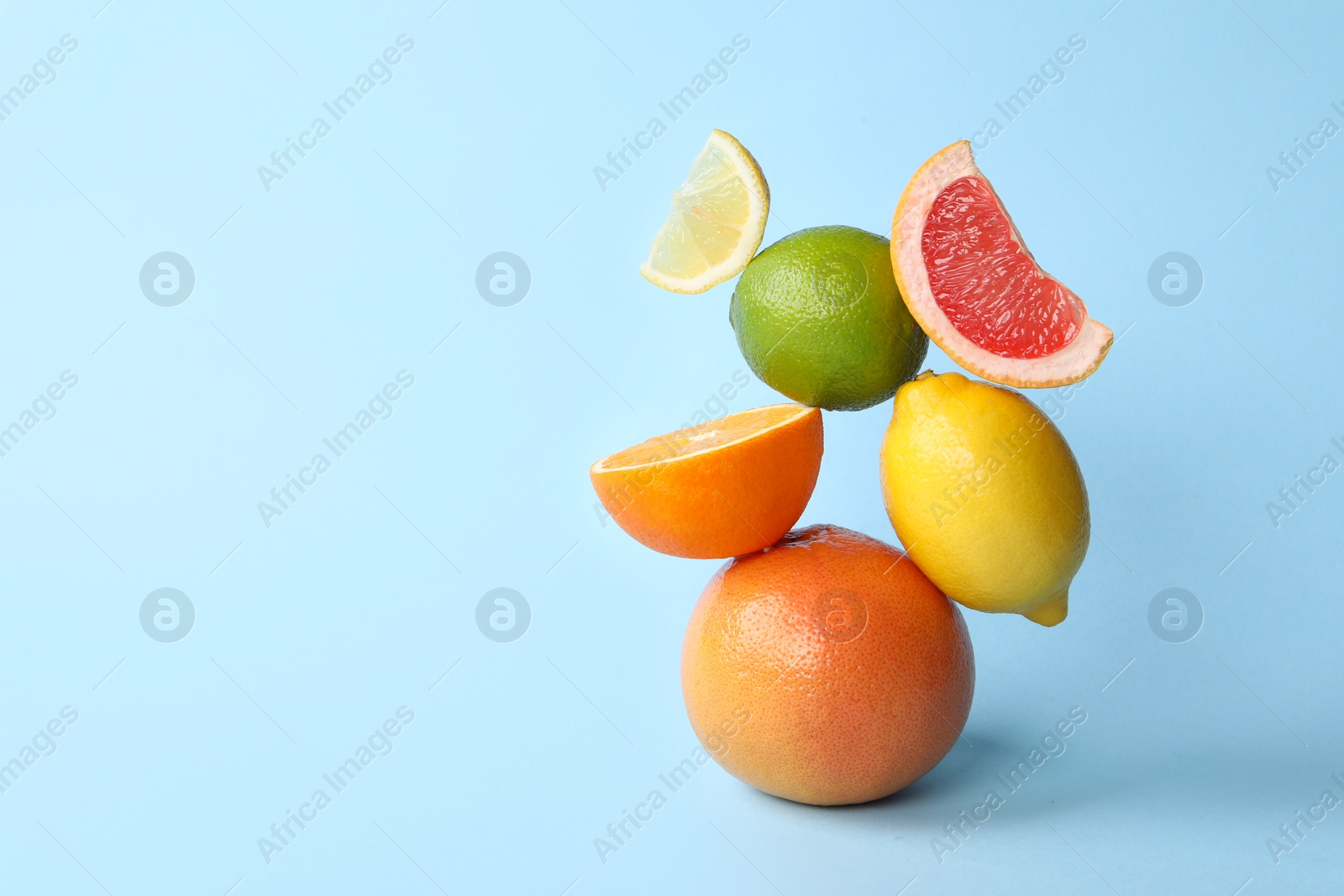 Photo of Fresh ripe citrus fruits on light blue background, space for text