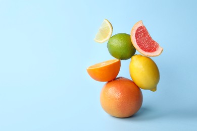 Fresh ripe citrus fruits on light blue background, space for text