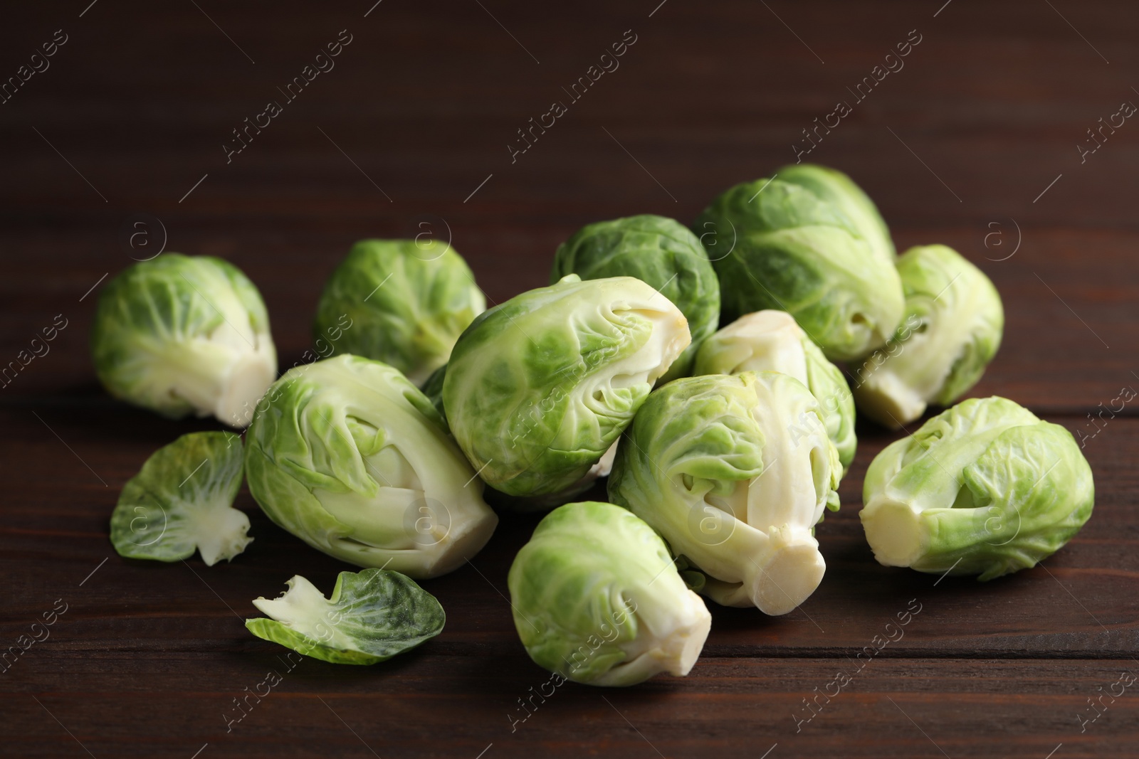 Photo of Fresh Brussels sprouts on brown wooden table, closeup