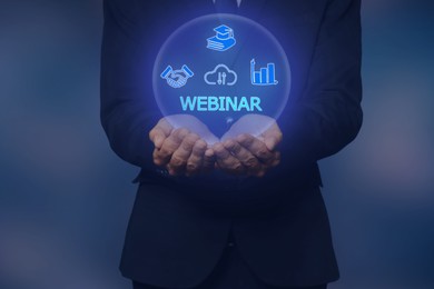 Image of Webinar. Businessman holding virtual icons on color background, closeup