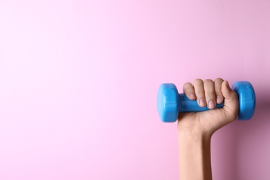 Photo of Woman holding vinyl dumbbell on color background, closeup with space for text