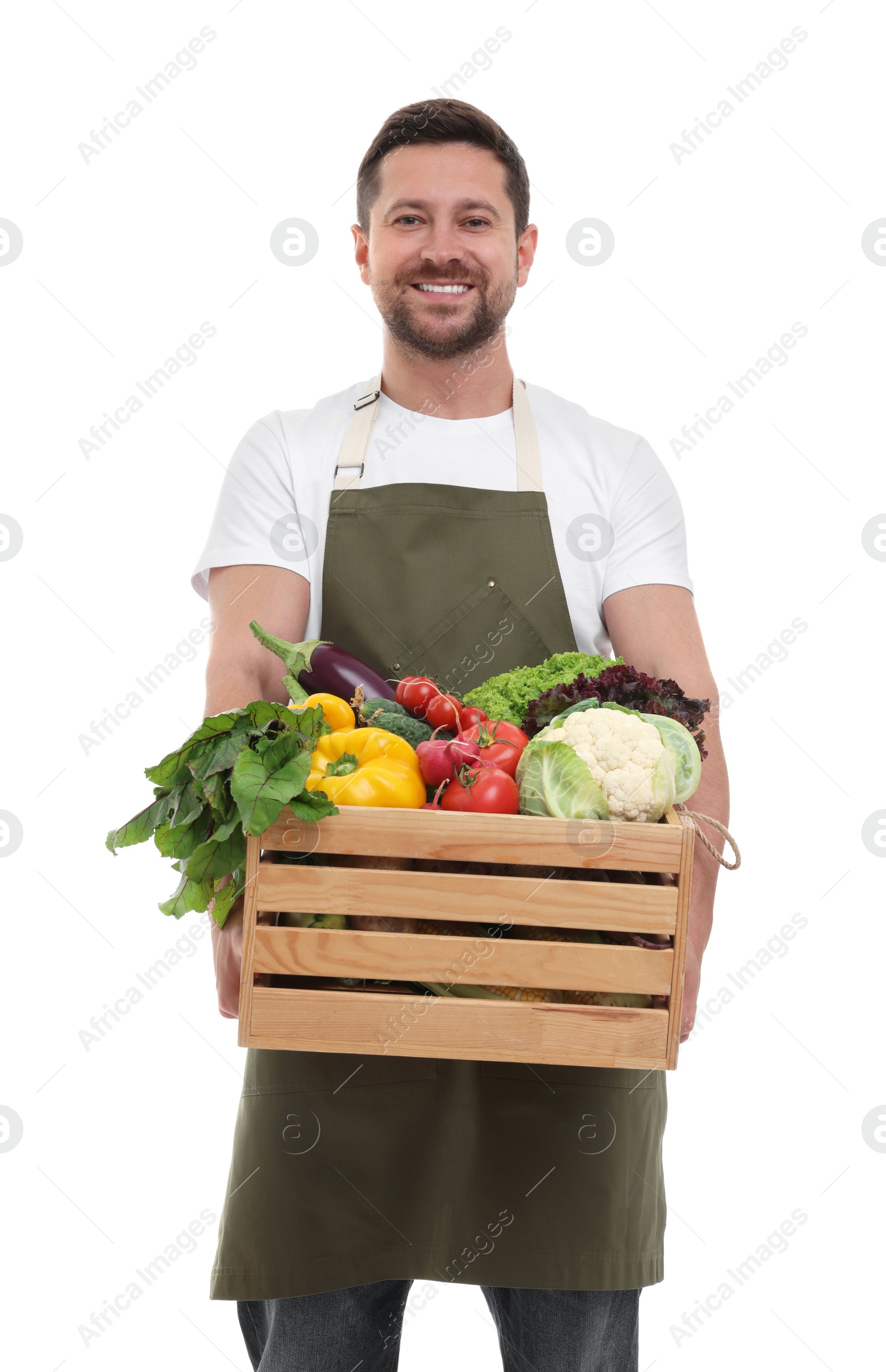 Photo of Harvesting season. Happy farmer holding wooden crate with vegetables on white background